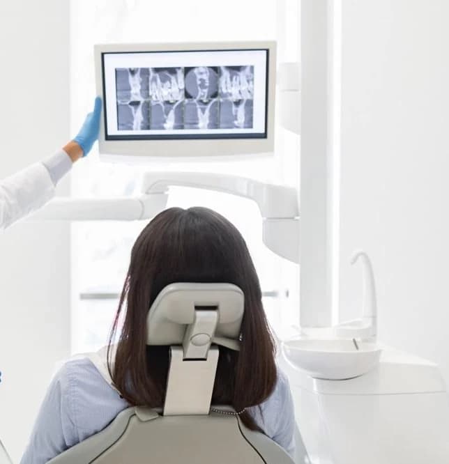 A patient reviewing their 3D scan and implant bridge treatment plan with the dentist
