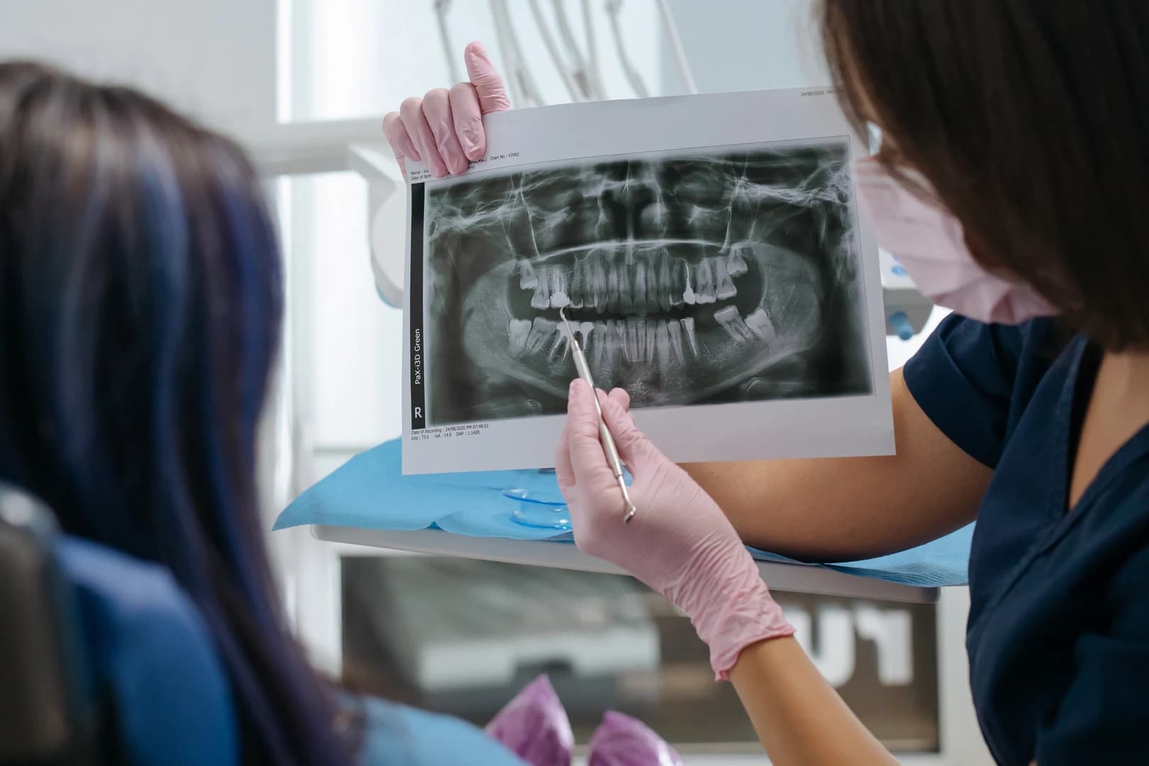 A dentist reviewing X-rays of the tooth with the patient before the extraction