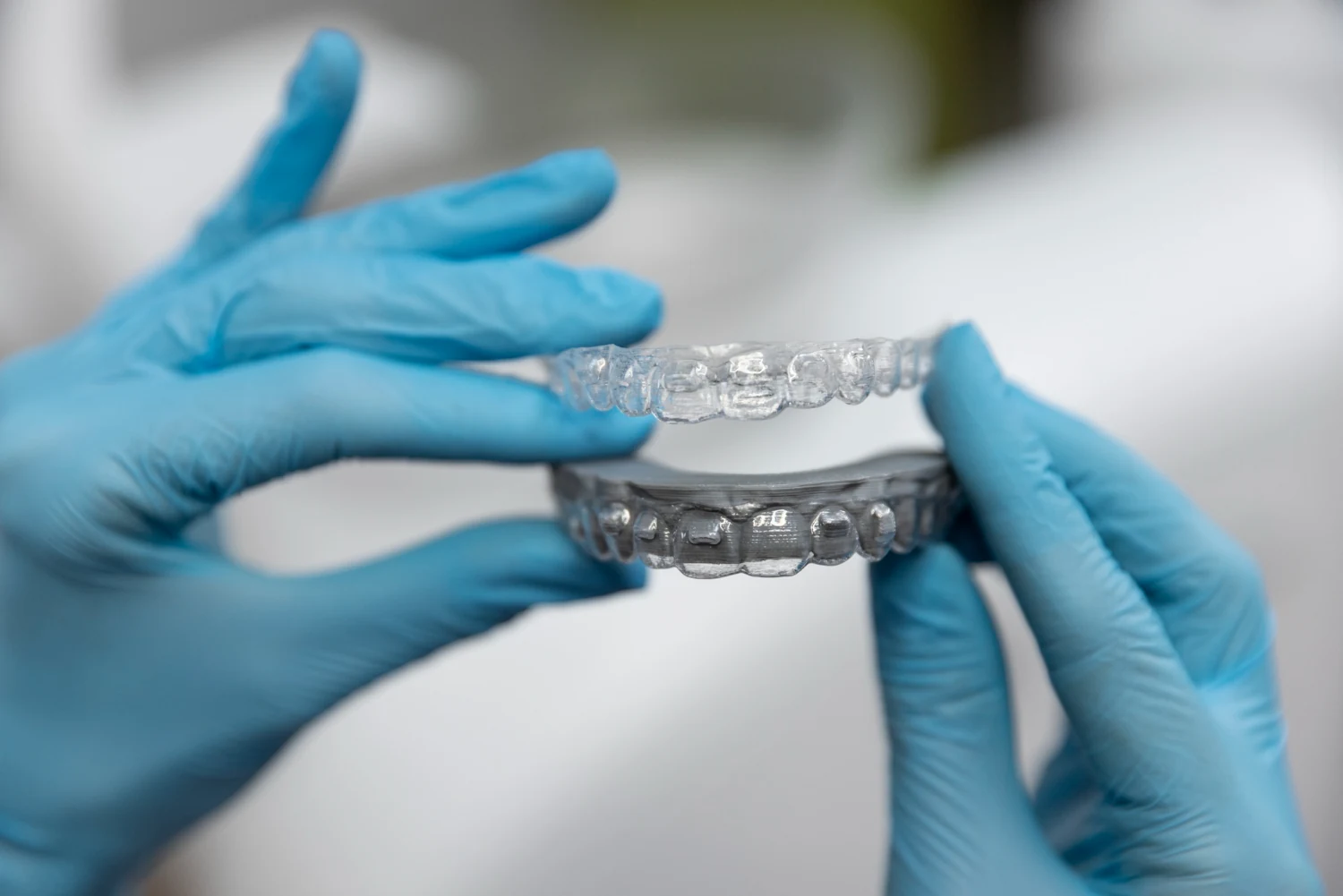 A smiling woman holding a clear, removable aligner