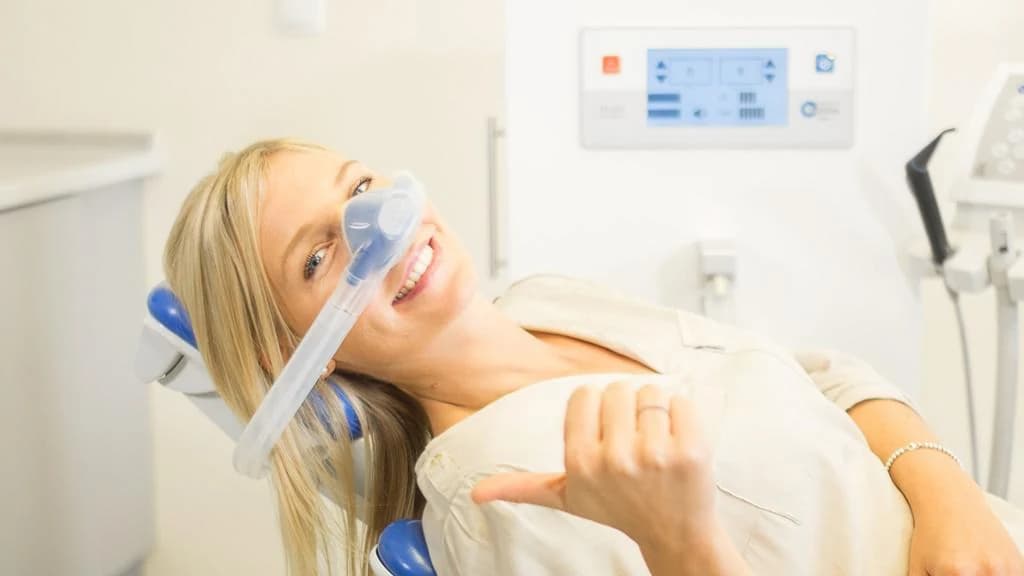 Patient relaxed in the chair breathing nitrous oxide through a nasal mask, giving a thumbs up