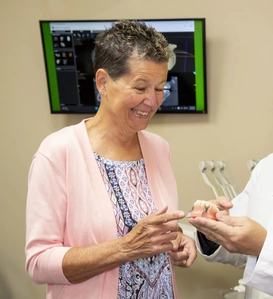 Patient smiling confidently with implant-supported dentures