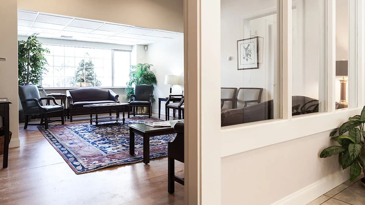 The waiting room at Peterborough Family Dental & Implant Center, with leather armchairs around a rug by a large window