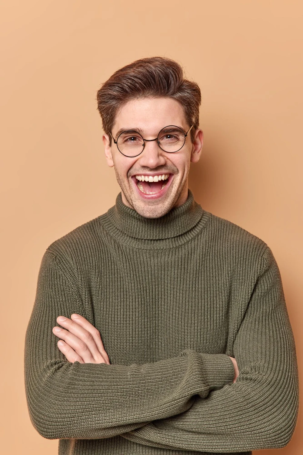 A smiling woman in a blue sweater on a pink studio background