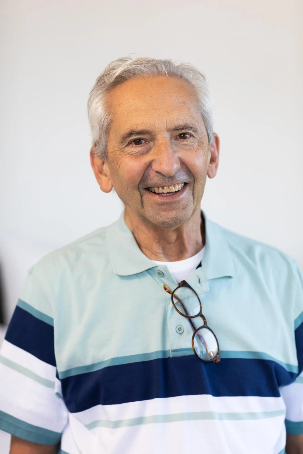 A cheerful older man in a yellow beanie on a purple studio background