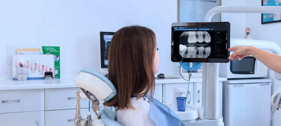 A patient in the chair reviewing her digital X-rays on screen with the dentist